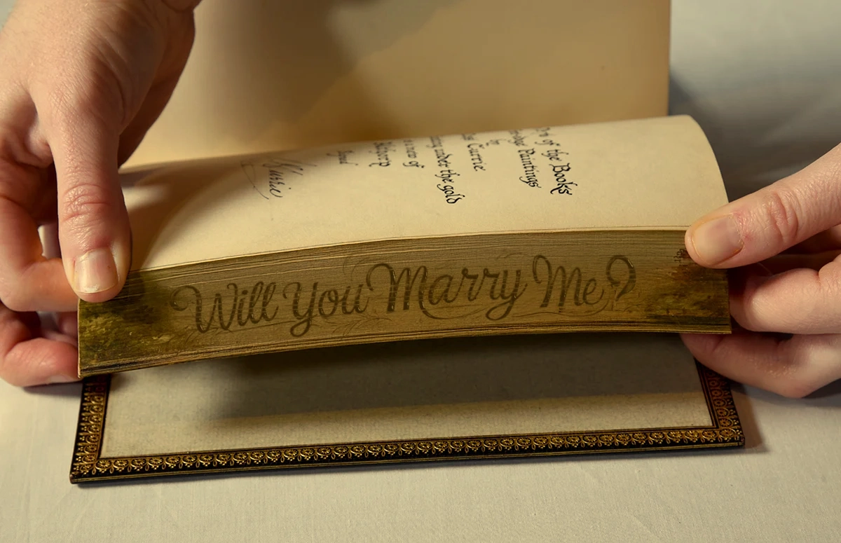 Hidden fore-edge message revealed when pages are fanned showing 'Will you marry me?'